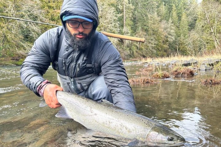 Person in fishing gear holding a large fish in a river.
